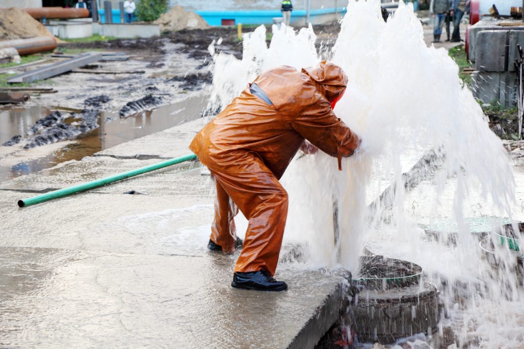 Worker in overalls eliminates breakthrough of sewerage systems.