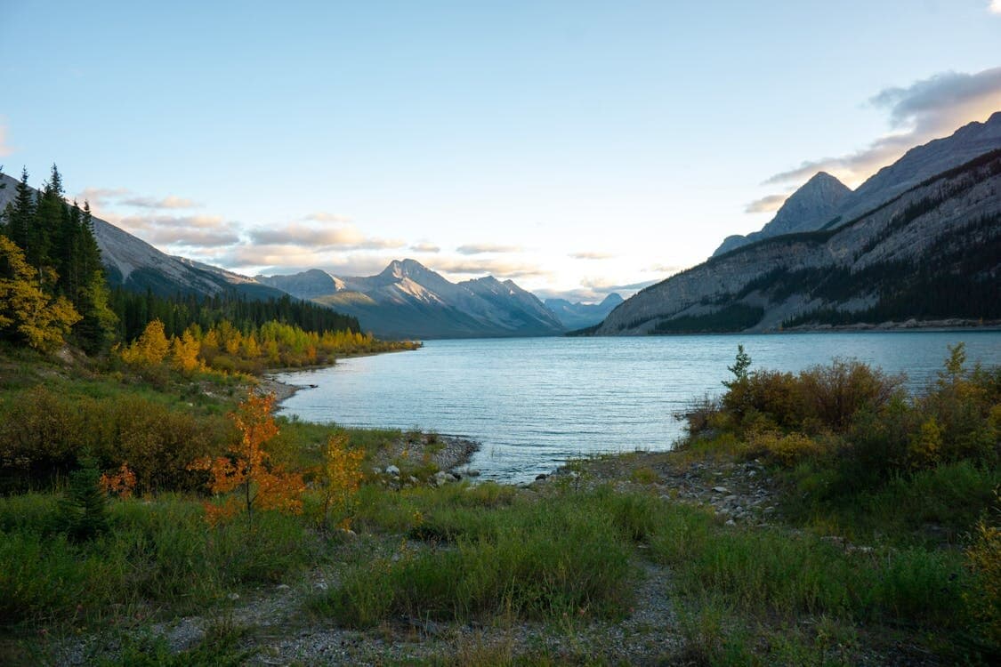 Mountain lake at dusk framed by autumn foliage and snow-dusted peaks